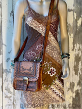 Load image into Gallery viewer, Hand tooled brown leather boho crossbody saddle bag with adjustable strap styled on mannequin in bohemian lace dress.