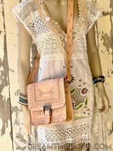 Load image into Gallery viewer, Tan genuine leather hand tooled saddle crossbody bag with floral tooling, vintage buckle and adjustable strap on mannequin.