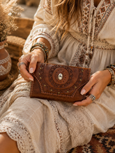 Load image into Gallery viewer, Antique brown hand tooled leather wallet with mandala design and stone detail, styled with a boho dress.