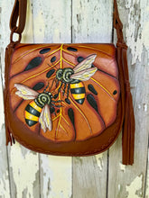 Load image into Gallery viewer, Bee Story hand painted leather crossbody bag hanging, featuring bee artwork on monstera leaf

