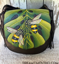 Load image into Gallery viewer, Bee Story hand-painted leather crossbody bag featuring bees on a green monstera leaf, handcrafted boho bag by Dreamtime Boho
