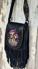 Load image into Gallery viewer, Side angle of Mushroom Magic black leather crossbody bag showing hand-painted mushroom flap, braided edging and long leather fringe.
