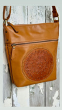 Load image into Gallery viewer, Angled view of tan genuine leather mandala crossbody bag showing the hand-tooled front panel and practical front zip pocket. Designed in Australia by Dreamtime Boho.