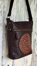 Load image into Gallery viewer, Side view of handcrafted chocolate brown leather boho bag showing the detailed hand-tooled mandala, front zip pocket and adjustable leather strap.