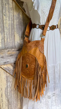Load image into Gallery viewer, Model wearing the Desert Bloom hand tooled tan leather crossbody bag with long fringe and adjustable strap.