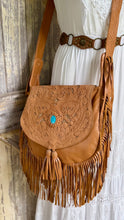 Load image into Gallery viewer, Desert Willow hand tooled tan leather fringe crossbody bag styled with a flowing white boho dress, featuring a turquoise gemstone and adjustable strap.