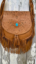 Load image into Gallery viewer, Close-up of the Desert Willow tan leather crossbody bag featuring intricate hand-tooled floral detailing, turquoise gemstone and leather fringe.