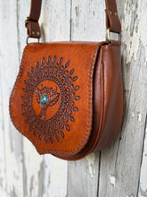 Load image into Gallery viewer, Rear view of Desert Wings mandala hand tooled leather crossbody bag showing genuine leather back and secure zip pocket.