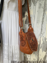 Load image into Gallery viewer, Side view of Floral Spirit hand tooled leather boho bag in tan with adjustable strap and hand carved floral detail.