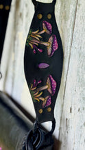 Load image into Gallery viewer, Detailed hand-tooled leather crossbody strap featuring colourful purple mushroom artwork on genuine black leather with brass stud accents