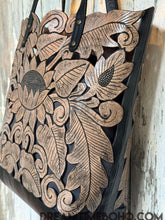 Load image into Gallery viewer, Side view of antique black lotus hand tooled leather tote bag with structured shape and shoulder straps