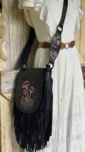 Load image into Gallery viewer, Black fringed leather crossbody bag styled with a white boho dress, featuring colourful hand-painted mushrooms and adjustable leather strap.