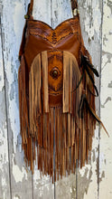 Load image into Gallery viewer, Close up of Rustic Feather genuine leather boho bag featuring hand tooled detailing, gemstone centre and long leather fringe.