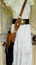 Load image into Gallery viewer, Black and tan Sahara Moon mandala hand-tooled leather fringe boho crossbody bag worn on model, featuring feather accents and long flowing fringe