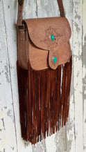 Load image into Gallery viewer, Angled view of tan leather fringe bag showing turquoise stones, hand-tooled front flap and long double-layered suede fringe.