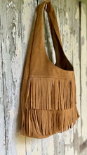 Load image into Gallery viewer, Side angle view of tan suede leather fringe shoulder bag with flowing layered fringe and relaxed bohemian styling